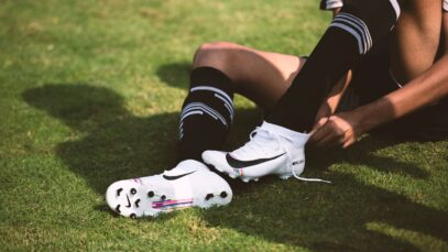 Joueur laçant des chaussures de football blanches sur une pelouse