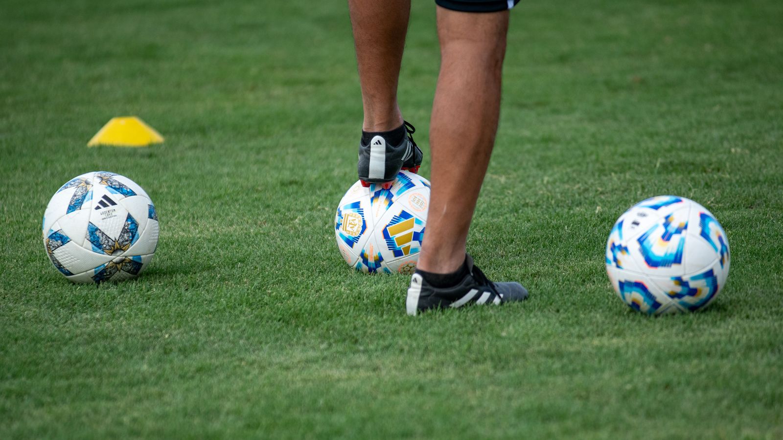 Chaussures de football noires entourées de ballons et de plots d'entraînement